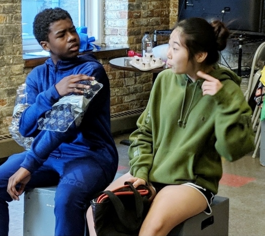 Two youth actors performing a scene with props